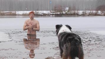 Man and Dog by Partially Frozen Lake in Winter Forest Setting video