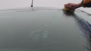 A man washes the windshield of a car with a rag and pours plenty of water on it. video