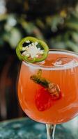 A cocktail with a strawberry garnish and jalapeno photo