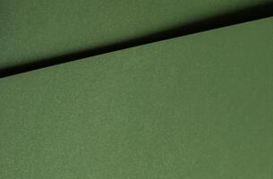 Moss green paper background with a smooth matte texture and subtle geometric lines. Deep forest and photo