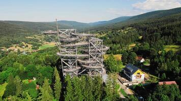Aerial view of Sky Walk spiral observation tower in Sweradow Zdroj, Poland, surrounded by green forests. Popular tourist attraction with breathtaking panoramic views of surrounding mountains video