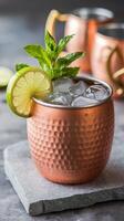 Moscow mule ice cold cocktl in copper cup with lime and and mint on gray stone background copy space photo