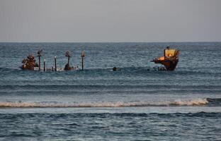 Waves Coming Ashore Around the Remains of a Wreck photo