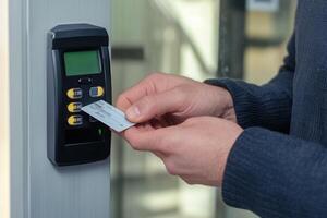 Person scanning an access card on a security keypad for entry, emphasizing technology and security in workplaces photo