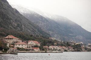 Serene coastal village nestled between mountains and water at dusk, featuring traditional architecture of Montenegro and a tranquil atmosphere photo