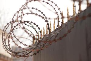 Razor wire coiled atop a security fence providing protection and deterrence in an urban environment during the daylight hours photo