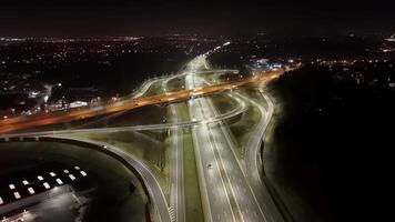 Aerial view of illuminated highway interchange at night, flowing traffic and city lights in the background. video