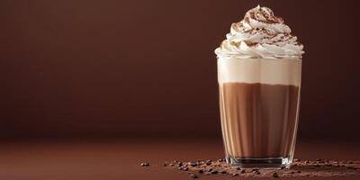 Creamy chocolate shake topped with whipped cream and cocoa in a glass on a brown background photo