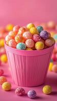 Colorful candy balls in a pink bucket surrounded by sweets on a vibrant pink background photo