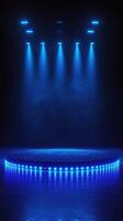 Bright blue lights illuminate a circular stage in a darkened venue, creating an atmosphere ready for a performance photo