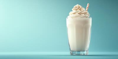 Creamy vanilla shake topped with whipped cream and a striped straw against a soft blue background photo