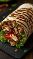 Grilled chicken wrap with fresh vegetables on a dark stone surface ready to be served for a delicious meal photo