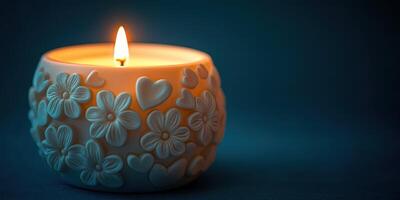 Decorative candle with floral and heart design illuminating a dark background photo