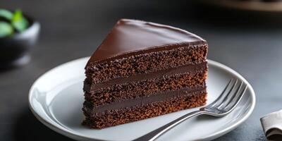 Chocolate cake slice served on white plate with fork placed elegantly beside it at a cozy dessert setting photo