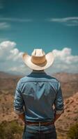 Cowboy stands on a mountain peak enjoying the vast landscape under a clear blue sky photo