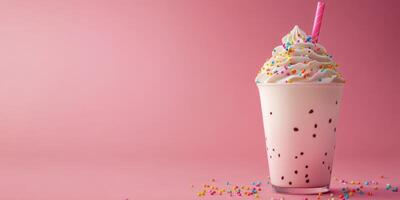 Delicious milkshake topped with whipped cream and colorful sprinkles against a pink backdrop photo