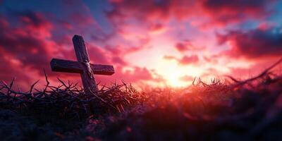 Cross amidst thorny branches at sunset with vibrant colors illuminating the sky photo