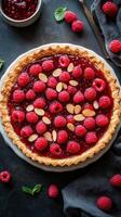 Fresh raspberry tart with a flaky crust and almond garnish on a dark background photo