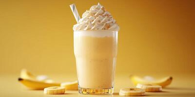 Creamy banana smoothie with whipped topping served in a tall glass surrounded by fresh banana slices photo