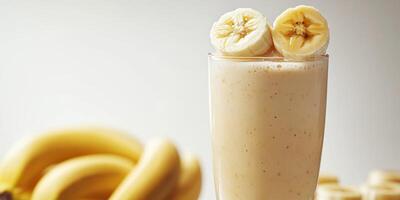 Banana smoothie served in a tall glass with fresh banana slices on top in a bright kitchen setting photo