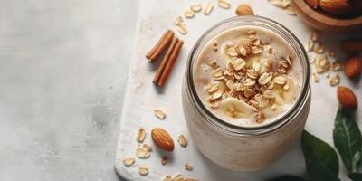 Smoothie with bananas, oats, almonds, and cinnamon on a wooden surface garnished with nuts and leaves photo