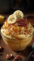 Delicious banana pudding dessert with caramel and nuts served in a glass bowl photo