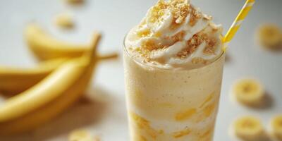 Creamy banana shake topped with whipped cream and crunchy crumbs in a clear glass photo