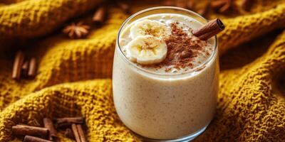 Creamy banana smoothie with cinnamon served on a cozy knitted backdrop photo