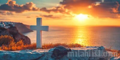 Sunset over the ocean with a white cross on a rocky coastline in a serene landscape photo