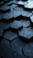 Textured black hexagonal tiles create an intriguing pattern with subtle light reflections in a dimly lit environment photo