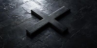 Dark wooden cross resting on a textured stone surface illuminated by soft light photo