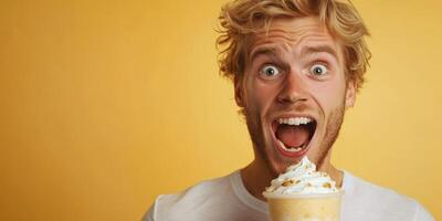 Man joyfully enjoying a dessert beverage with whipped cream against a bright yellow background photo