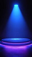 Spotlight illuminates a circular stage design with blue and purple lighting in a darkened venue photo