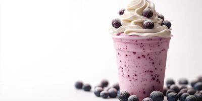 Creamy berry smoothie topped with whipped cream and blueberries served in a clear cup photo