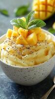 Creamy mango dessert topped with fresh mango cubes and mint in a rustic bowl at a bright kitchen photo