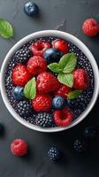 Fresh berry bowl with blackberries, raspberries, blueberries, and cherries garnished with mint leaves in a modern setting photo