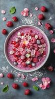 Vibrant bowl of berry dessert garnished with edible flowers and mint on a textured background photo