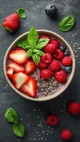 Fresh berry bowl with chia seeds and mint garnishing on a dark textured background photo