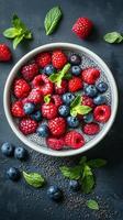 Fresh berry bowl with mint on dark background, showcasing vibrant colors and textures from various fruits and seeds photo