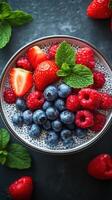 Fresh berry bowl with chia seeds and mint on a dark surface photo