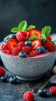 Fresh berry salad with strawberries, blueberries, and raspberries served in a textured bowl with mint garnish on a dark background photo