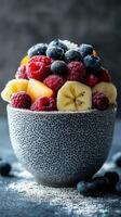 Colorful assortment of fresh fruits served in a textured bowl on a dark background during a bright morning photo