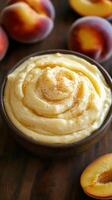 Creamy peach dessert served in a bowl surrounded by fresh peaches on a wooden table photo