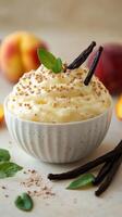 Creamy dessert topped with vanilla pods and mint leaves, featuring fresh peach slices in the background photo