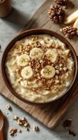 Delicious bowl of oatmeal topped with banana slices and walnuts on a wooden table photo