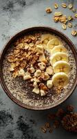 Healthy chia seed pudding topped with banana slices and granola on a textured grey background photo