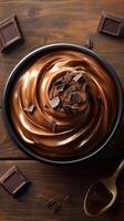 Delicious chocolate mousse served in a black bowl with chocolate shavings on wooden table photo