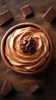 Decadent chocolate mousse served in a wooden bowl with chocolate pieces on a rustic wooden surface photo
