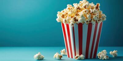 Freshly popped popcorn served in a striped container against a vibrant blue background photo