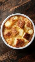 Delicious bread pudding baking in a white ceramic dish on a rustic wooden table during a cozy afternoon photo